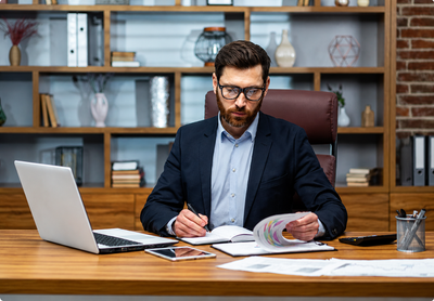 Professional businessman reviewing financial reports and compliance documents in a modern office for Anti-Money Laundering (AML) and Financial Crime Prevention training course.
