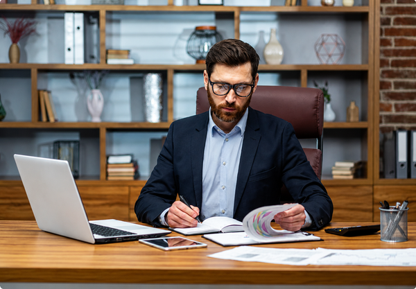 Professional businessman reviewing financial reports and compliance documents in a modern office for Anti-Money Laundering (AML) and Financial Crime Prevention training course.
