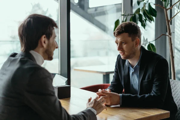 Two businessmen having a serious discussion at a table in a modern office.